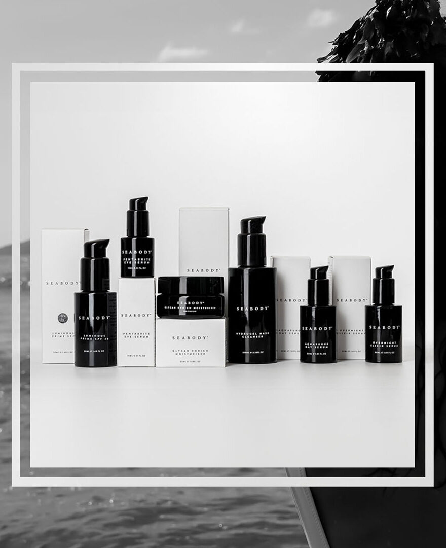 Seabody luxury seaweed skincare bundles in the moddle with a woman at the beach in background.jpg