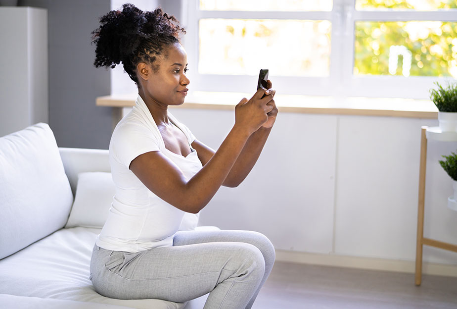 Woman looking at her phone but sitting upright with good posture